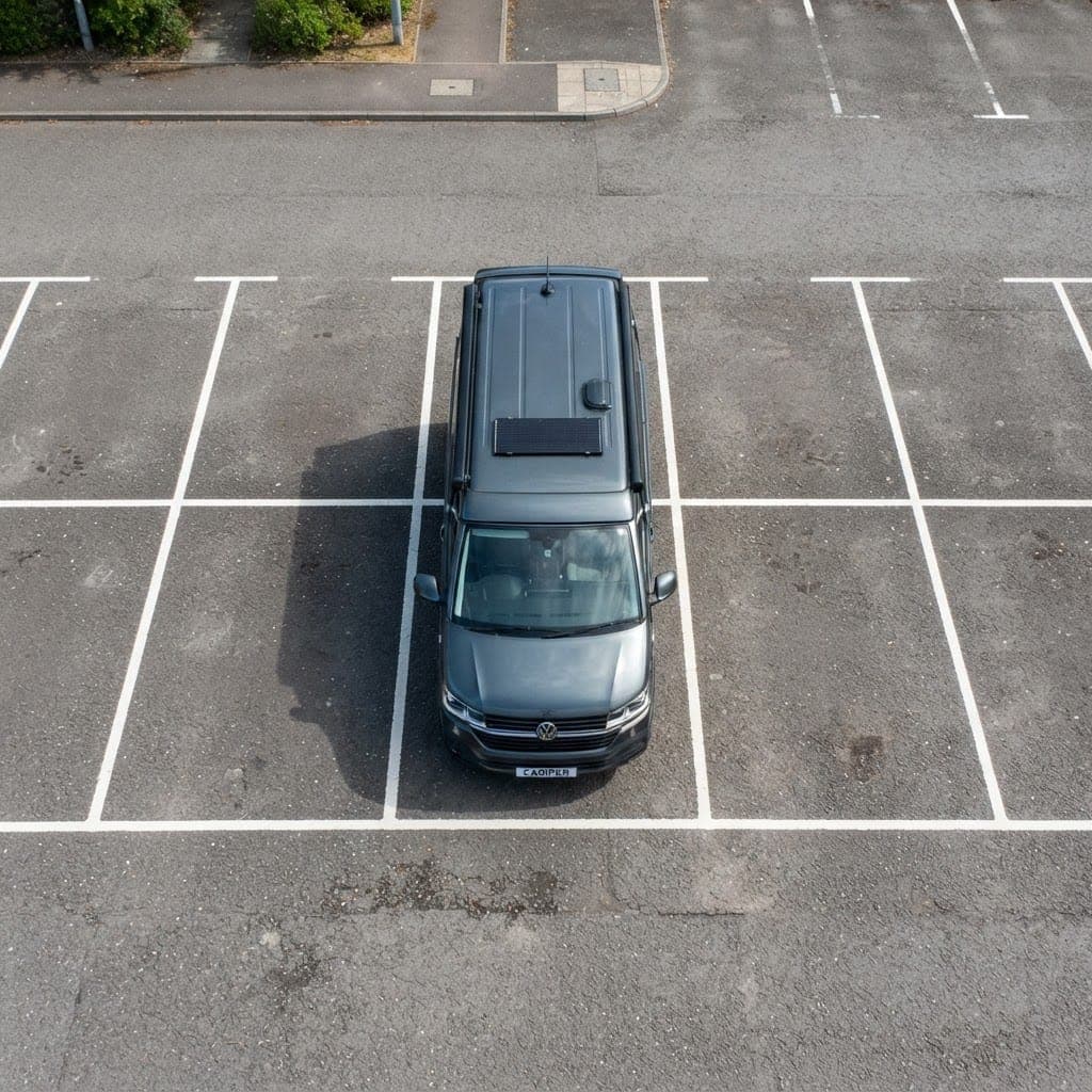 Top-down view of a dark VW Transporter campervan parked within a marked UK parking bay